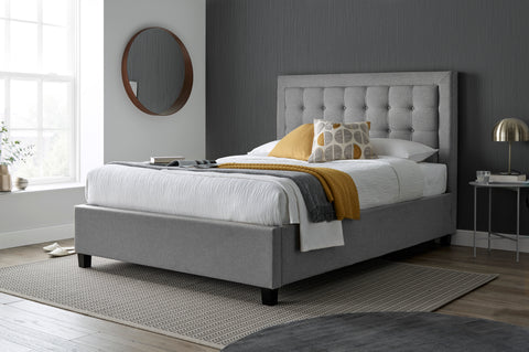 Brandon grey fabric ottoman bed with buttoned headboard styled in modern bedroom setting