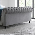 Osborne grey velvet chesterfield ottoman bed with tufted rolled footboard in a bright bedroom setting