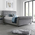 Osborne grey velvet chesterfield ottoman bed in a modern bedroom with large windows