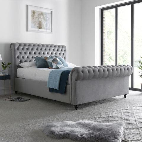 Osborne grey velvet chesterfield ottoman bed in a modern bedroom with large windows