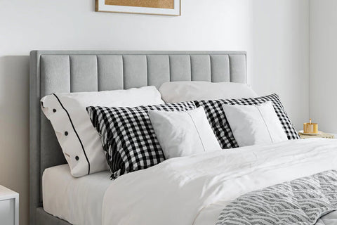 Rhodes grey velvet ottoman bed with contemporary headboard and checkered pillows in a bedroom setting