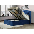 Warwick blue velvet wingback ottoman bed with mattress base lifted open showing under-bed storage in a styled bedroom