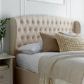 Close-up of Warwick velvet ottoman bed winged headboard in natural cream with vertical panel stitching