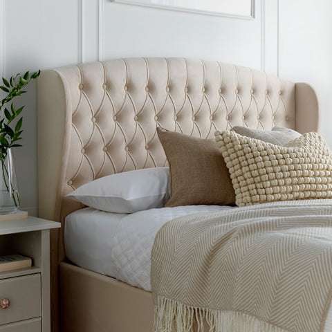 Close-up of Warwick velvet ottoman bed winged headboard in natural cream with vertical panel stitching